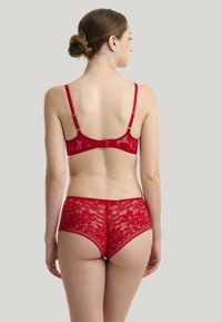 Rode kanten lingerieset met een bloemenpatroon, verstelbare bandjes en een haaksluiting op de rug. Getextureerde stof met een doorschijnende afwerking.