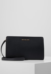 Pochette nera Michael Kors con superficie testurizzata, logo dorato, tracolla staccabile e forma rettangolare. Design semplice ed elegante.
