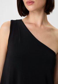 Schwarzes, ärmelloses Oberteil mit asymmetrischem Design, glatter, eleganter Textur und minimalem Detail. Dezente Schulterakzentuierung.