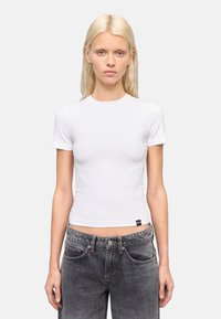 Witte aansluitende t-shirt met korte mouwen en een ronde hals, gemaakt van rekbare stof, gecombineerd met donkergrijze hoge taille jeans met zijzakken.