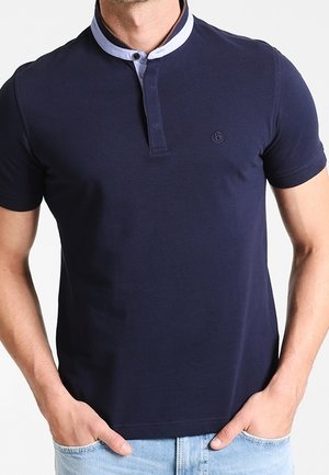 Marineblauwe polo met een contrasterende lichtblauwe kraag, korte mouwen en een knoopsluiting. Heeft een klein logo op de borst.