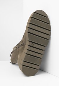 Botte de cheville en daim marron avec une fermeture éclair, dotée d'une semelle extérieure en caoutchouc texturé avec des rainures prononcées et d'une taille marquée de 37.