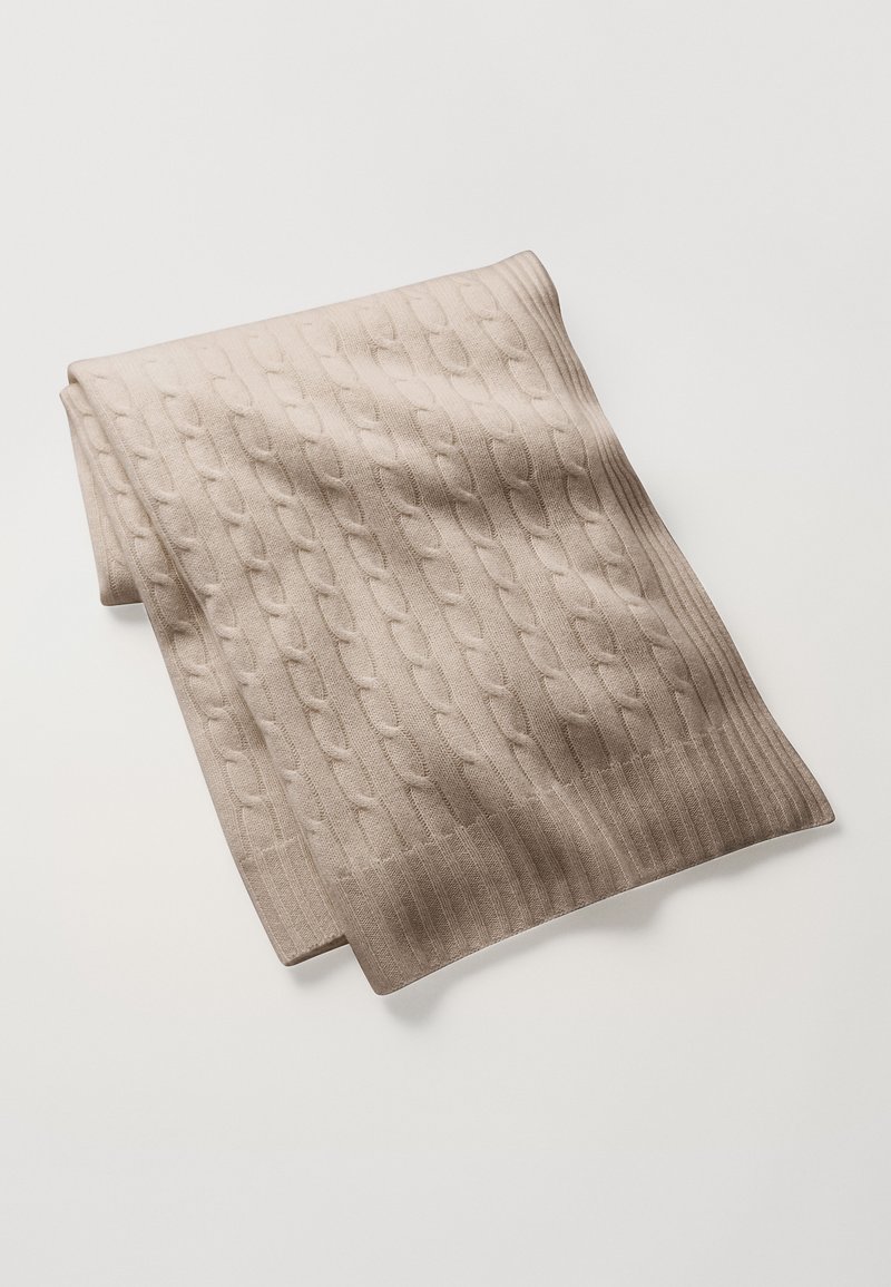 Cachecol de malha bege com padrão de tranças e bordas caneladas. O tecido parece suave e texturado, dobrado de forma arrumada para exibição.