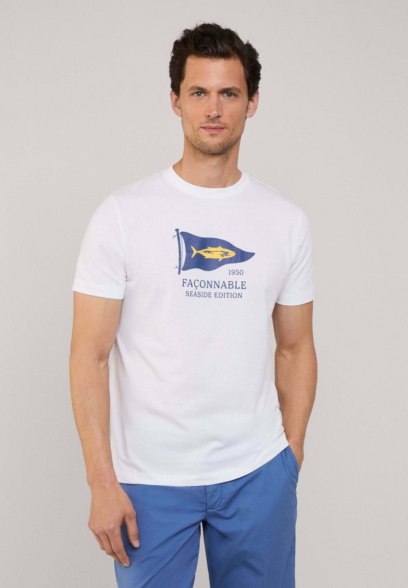 Camiseta de algodón blanca con un gráfico de una bandera de navegación azul, un pez amarillo y el texto "FAÇONNABLE 1950 SEASIDE EDITION". Mangas cortas, cuello redondo.