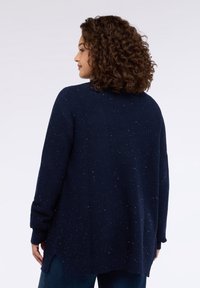 Maglione blu navy lavorato a maglia con una vestibilità ampia, caratterizzato da una texture screziata, maniche lunghe, scollo arrotondato e spacchi laterali all'orlo.