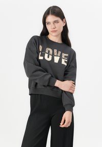 Felpa corta grigio scuro con maniche oversize, caratterizzata dalla parola "LOVE" in grassetto, lettering dorato luccicante, stampata sul davanti.