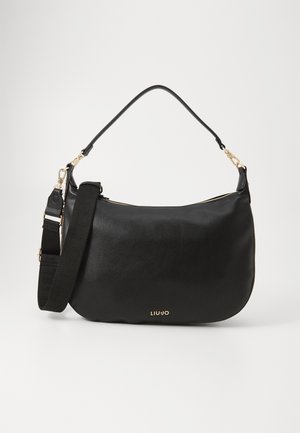 Sac à main en cuir noir au format courbé, avec des accessoires en or et une bandoulière amovible. Il présente une fermeture à glissière et un logo de la marque en relief.