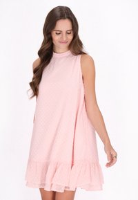 Rochie roz fără mâneci, cu un model texturat în puncte, margine franjurată și croială lejeră. Materialul pare ușor și aerisit, potrivit pentru vreme caldă.