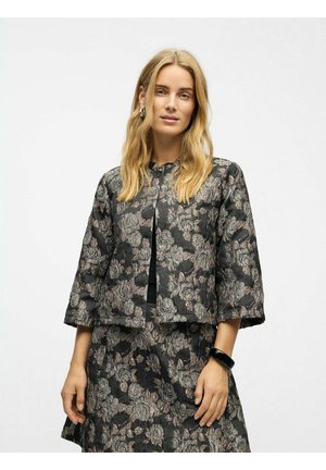 Schwarze Blütenjacke aus strukturiertem Stoff, mit Dreiviertelärmeln und rundem Ausschnitt. Kombiniert mit einem passenden Rock.