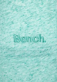 Turkusowy sweatshirt z okrągłym dekoltem, wykonany z teksturowanej tkaniny z delikatnym, melanżowym wzorem. Posiada haftowane logo "Bench." z przodu.