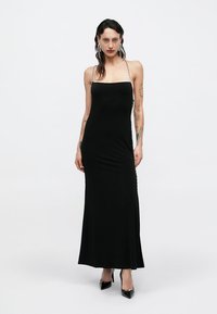 Μαύρο, αμάνικο maxi φόρεμα με ίσια λαιμόκοψη και σκισίματα στα πλάγια. Διαθέτει λεπτομέρεια με αλυσίδα κατά μήκος των πλευρών. Λείο, εφαρμοστό ύφασμα.