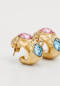 Gullringe med rosa og blå fasetterte steiner, med en glatt tekstur og små klare detaljer langs sidene.