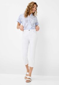 Chemise bleu clair à manches courtes avec motif floral ; pantalon blanc court ; sandales blanches avec boucle ; tissu lisse et coupe ajustée.