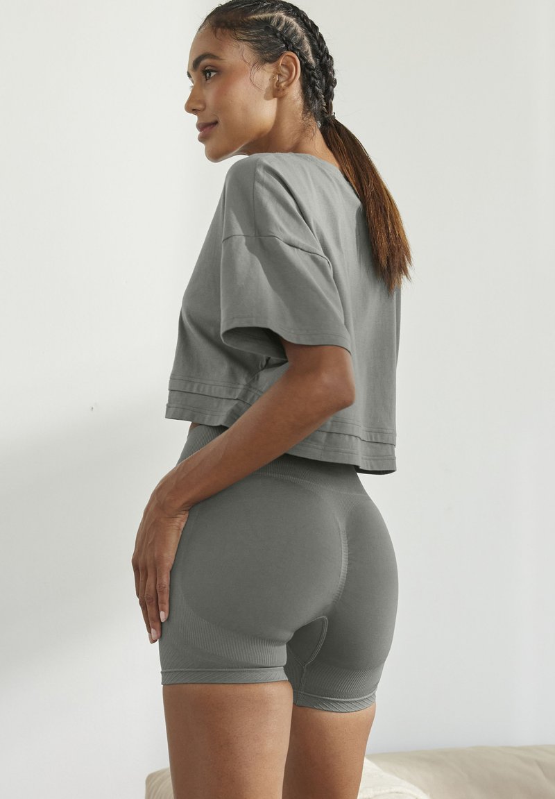 Grijze cropped t-shirt en bijpassende aansluitende shorts, gemaakt van gladde stof met een ribbelstructuur, die schone lijnen en een minimalistisch ontwerp tentoonstellen.