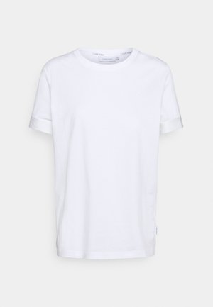 Maglietta bianca in cotone con scollo rotondo, maniche corte arrotolate e dettaglio discreto del logo sulla manica. Orlo dritto e vestibilità morbida.