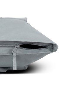 Sac en tissu gris avec une ouverture zippée sur le dessus, présentant une surface texturée et des coutures renforcées le long des bords.