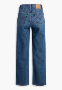 Jean en denim bleu à coupe droite vu de dos avec deux poches arrière, coutures marron et un patch de marque en cuir beige sur la ceinture.