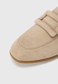 Chaussure en daim beige avec un bout arrondi, dotée de deux larges lanières sur le dessus et d'une semelle en caoutchouc lisse.
