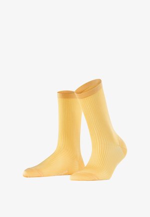 Paire de chaussettes jaunes côtelées mi-mollet présentées debout sur un fond blanc.