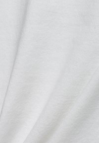 Nahaufnahme von weichem, weißem Strickstoff, der Textur und subtile Falten zeigt.