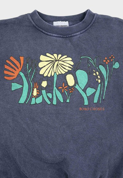 Camisa azul marino con diseños abstractos de flores en colores amarillo, naranja y verde azulado, y texto naranja "BOBO CHOSES" en la parte inferior derecha.