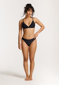 Juodas bikini rinkinys, kuriame yra voliotų trikampių formos liemenėlė ir aukšto liemens kelnaitės, pagamintas iš lygaus audinio su minimaliu dizainu ir be raštų.