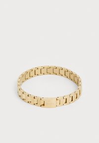 Brățară din metal auriu cu design de linkuri interconectate, având o suprafață netedă și un închizător cu logo gravat. Formă circulară, finisaj lucios.