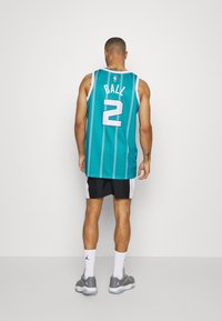 Teal koripallo paita, jossa on valkoiset raidat, selässä numero 2 ja teksti "BALL". Yhdistetty mustiin shortseihin ja harmaisiin lenkkikenkiin.