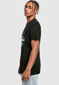 Sort bomulds t-shirt med korte ærmer, prydet med et farverigt grafisk design på forsiden. Lige snit, blød tekstur og rund halsudskæring.