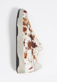 Sneaker z górą z bydła pokrytą brązowo-białym wzorem w plamki, z teksturowanymi akcentami ze skóry i szarym gumowym spodem.