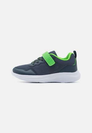 Chaussure de sport gris foncé avec des touches vertes, une bride en Velcro, une semelle blanche et une tige en tissu mesh, vue de côté sur fond blanc.