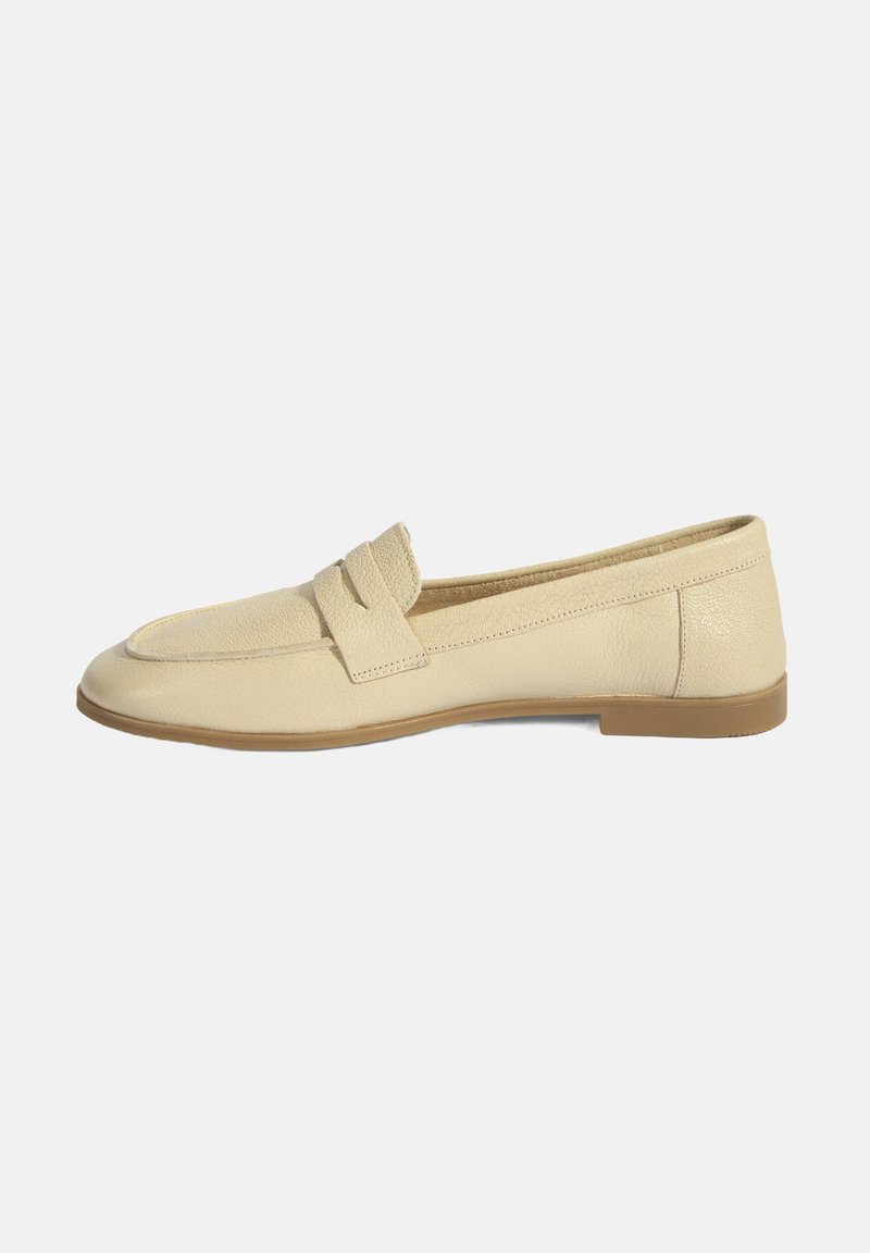 Beige leren moccasinschoen met een gladde textuur, voorzien van een eenvoudige band over de voet en een platte, lichtbruine zool.