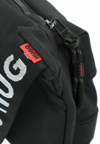 Borsa a spalla in nylon nero con un esterno texturizzato, tracolla regolabile con il marchio "HUGO" e chiusura con zip dotata di hardware rinforzato.