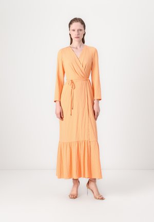 Wrap dress in textured orange fabric, long sleeves, belted waist, and a tiered hemline, paired with nude high-heeled sandals.