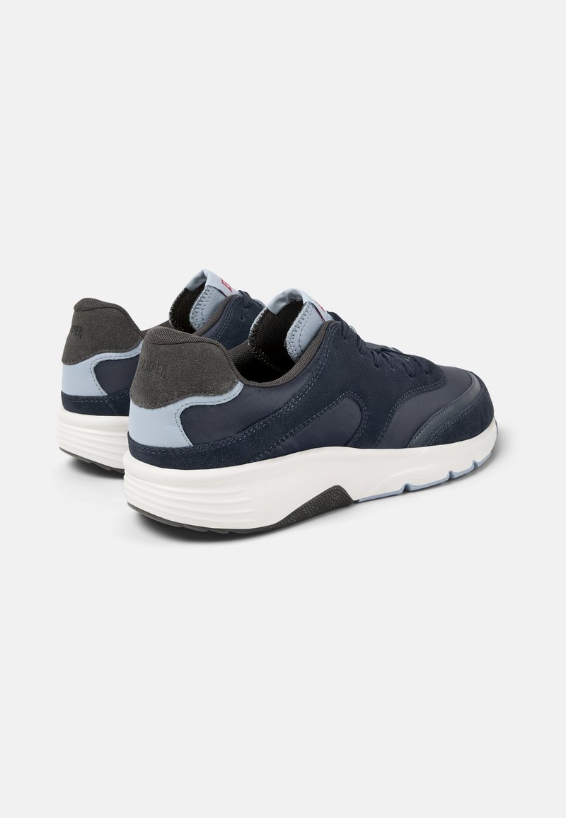Marineblaue Sneaker aus Wildleder und Mesh-Materialien, mit weißer Zwischensohle und grauem Fersenakzent, runder Form und strukturiertem Oberflächen.