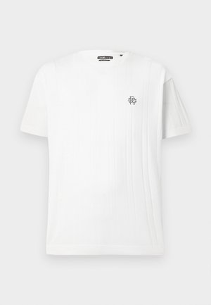 Hvit, kortermet strikket T-skjorte med vertikalt ribbemønster på høyre side og liten svart brodert logo på brystet.
