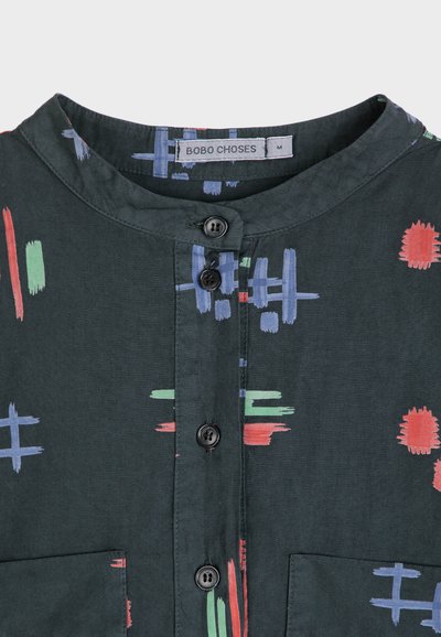 Camisa de cuello verde oscuro con patrones multicolores de pinceladas, presenta botones negros y un bolsillo en el pecho. Tejido suave.