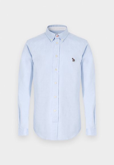 Chemise bleu clair à manches longues, col classique, boutons sur le devant et un petit détail de zèbre brodé sur la poitrine.