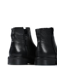 Czarne skórzane botki za kostkę o gładkiej fakturze, z boku zapinane na zamek i z niskim, grubym obcasem. Tył ma delikatnie wycięty kształt.