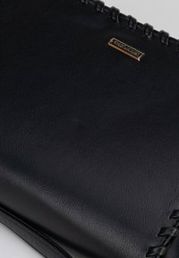 Borsa a tracolla in pelle nera con dettaglio intrecciato lungo il bordo. Presenta una piastra del logo in metallo dorato. Texture liscia, forma rettangolare.
