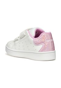 Baskets pour enfants blanches avec une tige en cuir lisse, accent en paillettes roses au niveau du talon, perforations pour la respirabilité, et sangle Velcro.