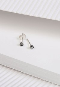 Silberne Ohrstecker mit einem schwarz-weißen gestreiften Knoten-Design, mit einer glatten Oberfläche und einem Schmetterlingsverschluss.