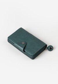 Portafoglio in pelle teal con superficie liscia, chiusura a zip perimetrale, pulsante a scatto e un accento in metallo circolare. Forma rettangolare compatta.