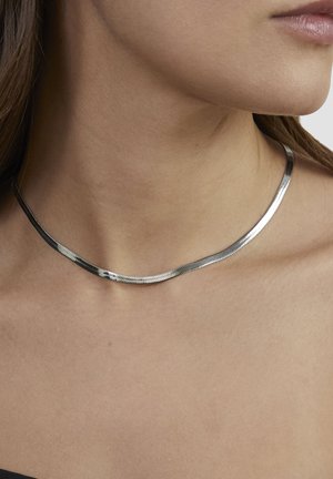 Silberne Choker-Halskette mit einem glatten, geschwungenen Design. Aus Metall gefertigt, mit feiner Struktur und polierter Oberfläche, die am Hals liegt.