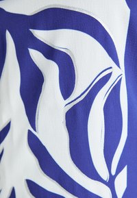 Textured fabric with a blue and white leaf pattern, featuring smooth shapes and clean edges, creating a contrasting design.