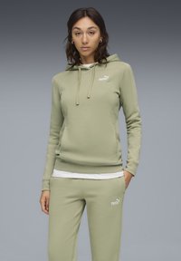 Lys grøn hættetrøje med snøre, kængurulomme og hvid Puma-logo. Sættes sammen med matchende sweatpants, der også har et lille logo.