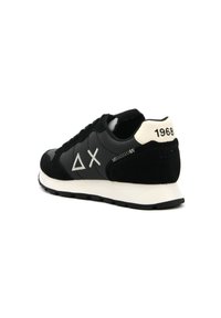Sneaker nera realizzata in materiali scamosciati e in pelle, con un tallone bianco recante il testo "1968" e un logo con forme geometriche in grigio.