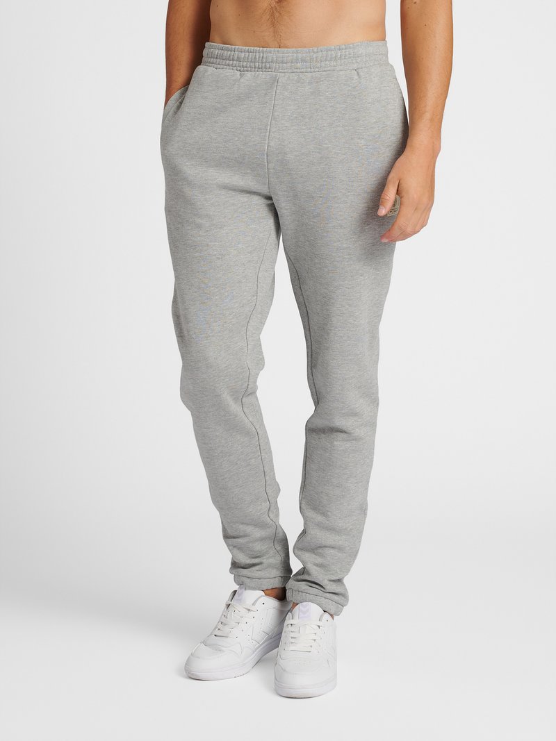 Grijze sweatpants gemaakt van zachte stof met een elastische tailleband en twee zijzakken. Draag met witte sneakers.
