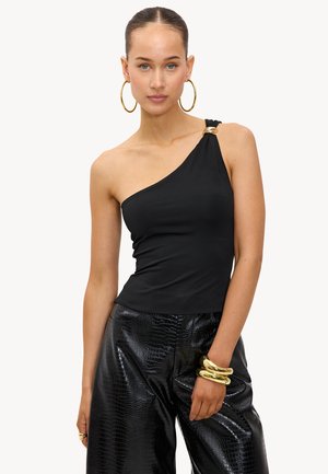 Haut noir à épaule unique en tissu extensible avec un accent doré à l'épaule. Associé à un pantalon noir brillant à motif crocodile.