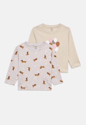 Two long-sleeve shirts: one beige with balloon graphic and one light purple featuring a dog pattern and white flowers. Cotton material.